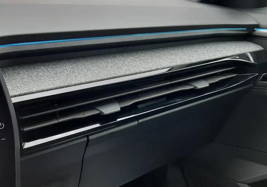 Détail de la planche de bord côté passager du Renault Austral Ph.2 gris schiste, avec bandeau décoratif bleu et aérateurs noirs.