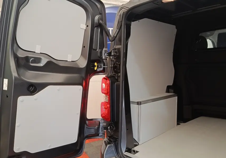 Vue arrière ouverte du Citroën Jumpy gris foncé 2025, montrant l'intérieur utilitaire avec cloison pleine et rangement blanc.