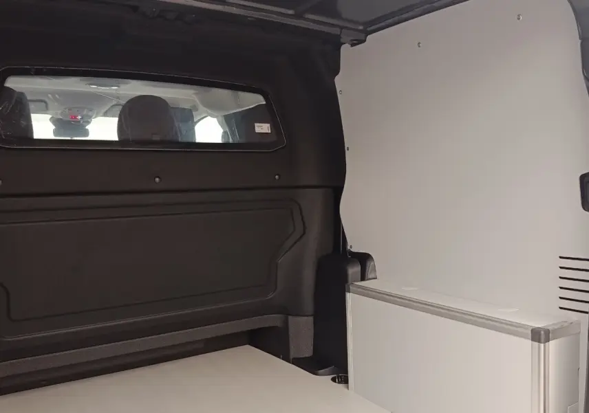 Vue intérieure arrière du Citroën Jumpy gris foncé, montrant la cloison vitrée pleine et l'espace de chargement.