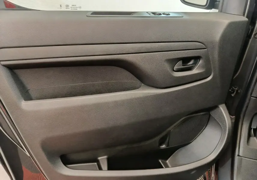 Vue rapprochée de la porte côté conducteur du Citroën Jumpy gris foncé, montrant la poignée et les commandes des vitres.