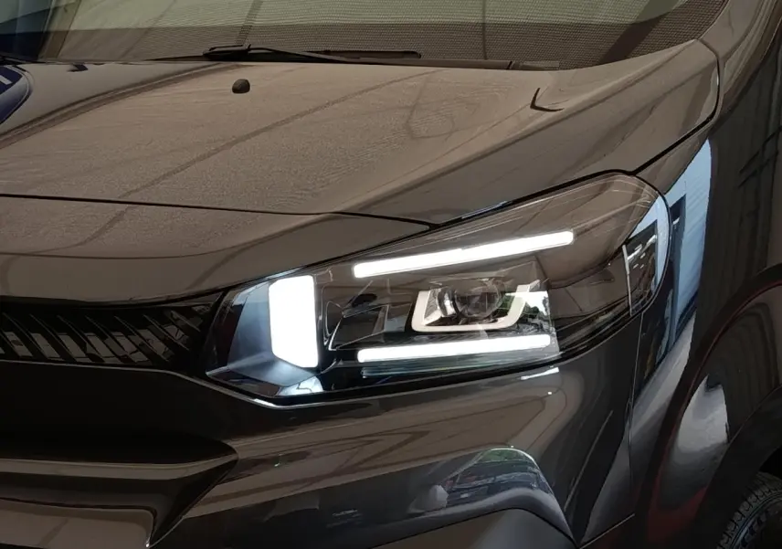 Gros plan sur le phare avant droit allumé d’un Citroën Jumpy gris foncé, soulignant son design moderne et lumineux.