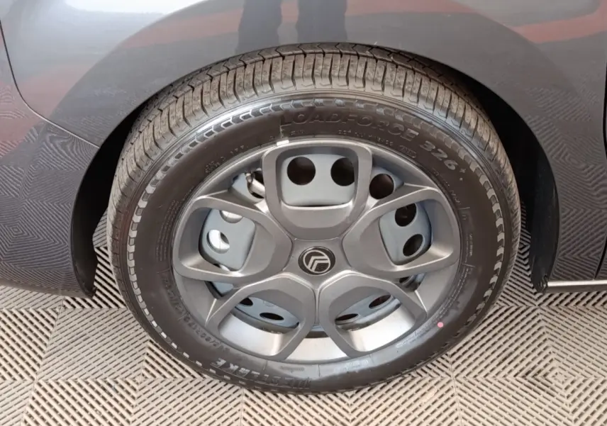 Gros plan sur la roue arrière droite d'un Citroën Jumpy gris foncé, mettant en valeur le pneu et l'aile du véhicule.