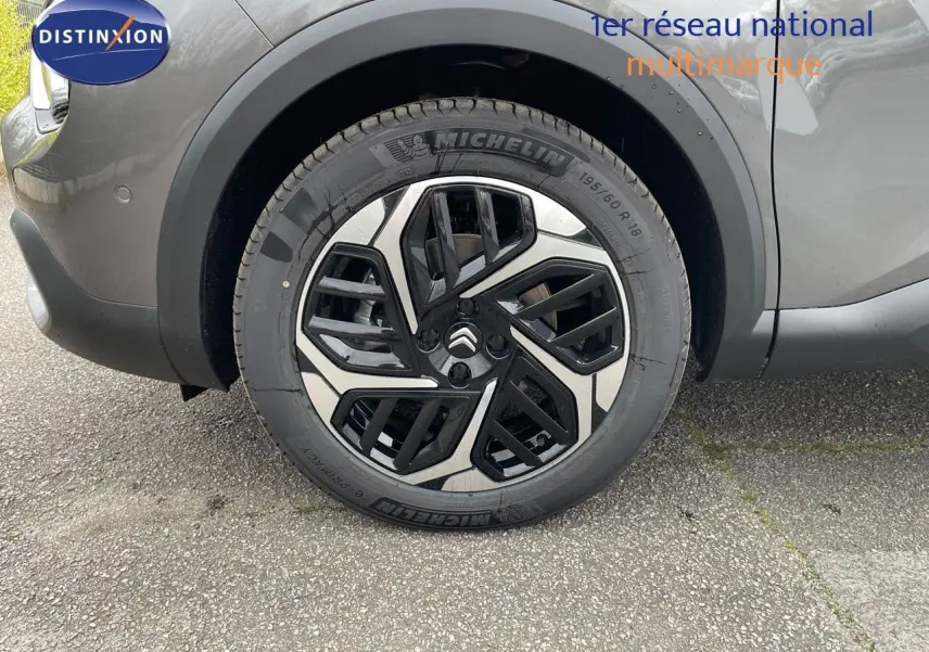 Gros plan sur la roue avant gauche de la Citroën C4 2024 gris platinium métal avec jante alliage bicolore distinctive.