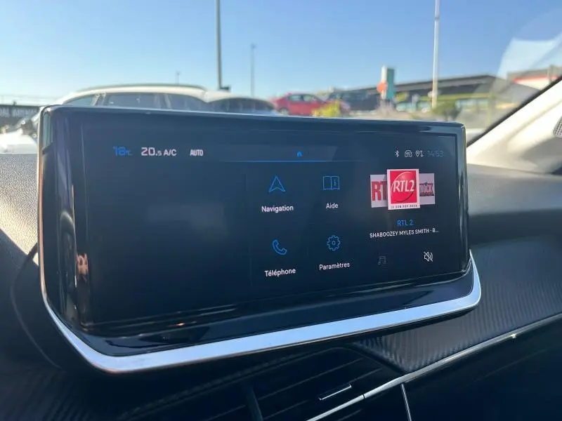 Écran tactile central du tableau de bord de la Peugeot 208 1.2 100ch Allure 2024, affichant navigation et radio.