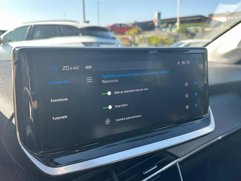 Écran tactile du système d'aide à la conduite dans l'habitacle d'une Peugeot 208 gris, vue de face.