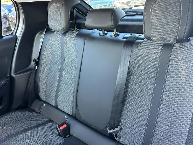 Vue intérieure des sièges arrière gris texturés de la Peugeot 208 1.2 100ch Allure 2024 avec appuie-têtes et ceintures de sécurité.