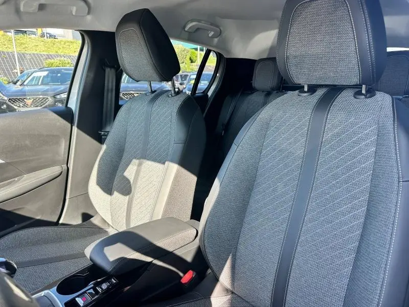 Intérieur du Peugeot 208 1.2 100ch S&S Allure 2024 montrant les sièges avant gris en tissu et cuir, côté conducteur et passager.