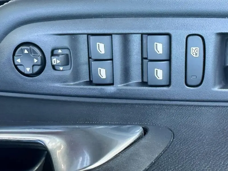 Panneau de commandes des vitres électriques côté conducteur d'une Peugeot 208 gris 2024 avec boutons de réglage des rétroviseurs.