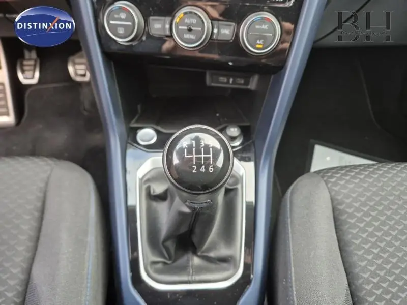 Le levier de vitesses manuel noir du Volkswagen T-Roc gris, vu de dessus entre les sièges avant.