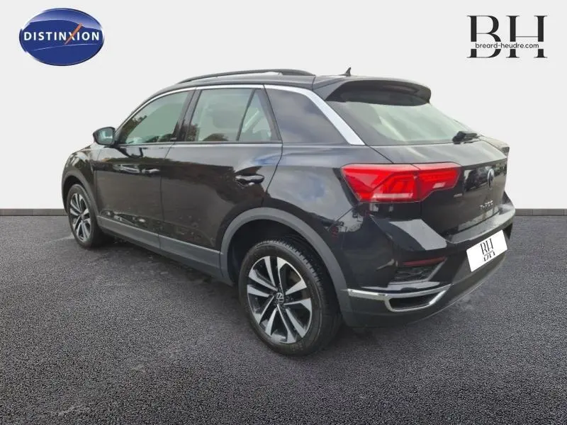 Vue 3/4 arrière droite d'un Volkswagen T-Roc gris avec jantes alliage et barres de toit chromées