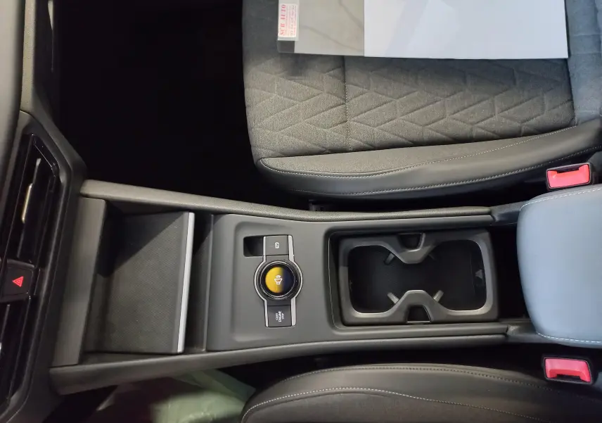 Vue plongeante sur la console centrale du Volkswagen Tiguan 2025, avec porte-gobelets et siège tissu gris à motifs géométriques.