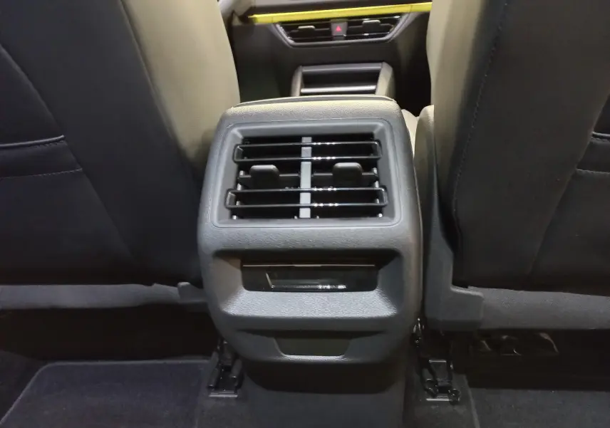 Buses d'aération arrière entre les sièges avant noirs du Volkswagen Tiguan 2025, intérieur sobre et fonctionnel.