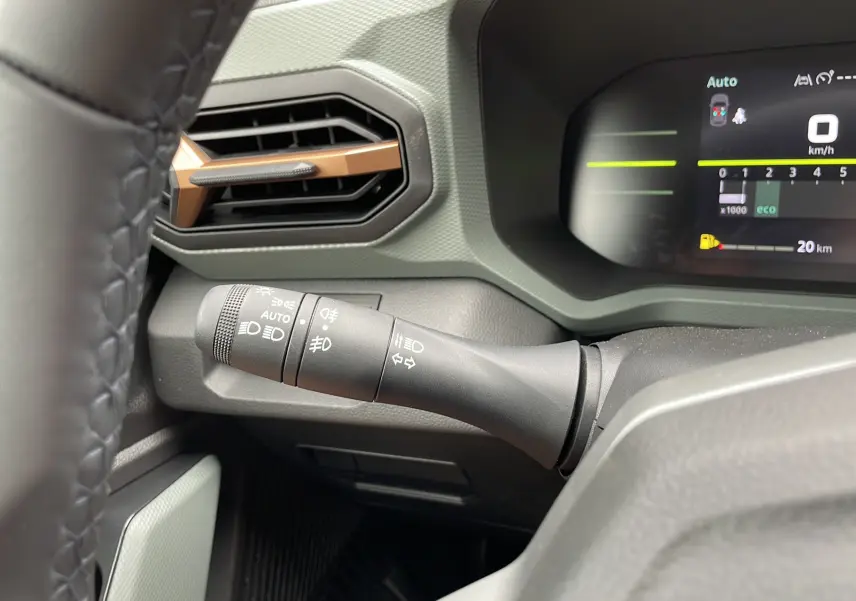 Gros plan sur la commande des feux et clignotants du tableau de bord kaki lichen du Dacia Duster 2025.