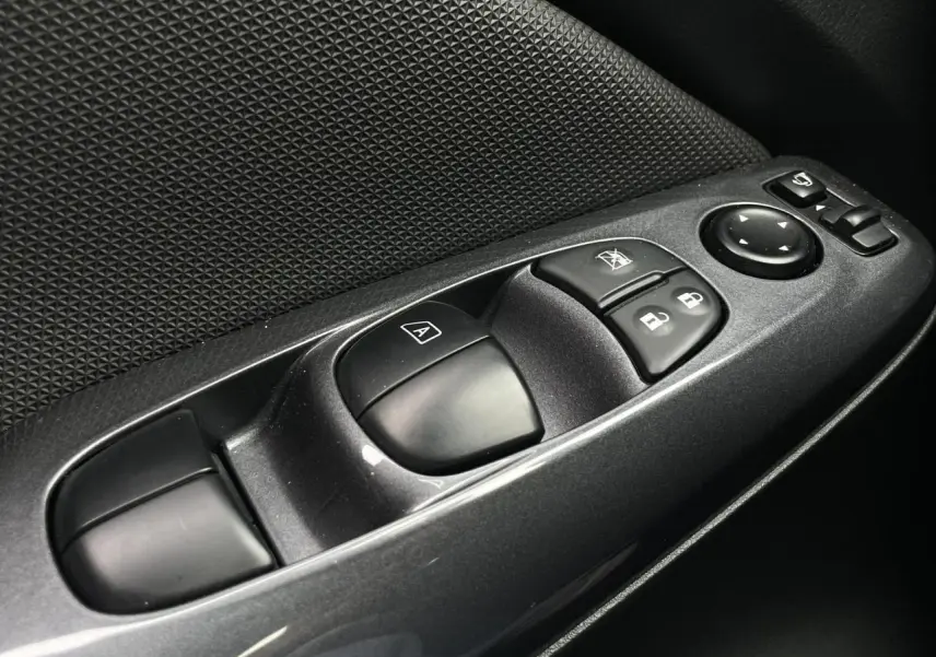 Gros plan sur les commandes de lève-vitres et rétroviseurs côté conducteur du Nissan Juke gris Silver 2024.