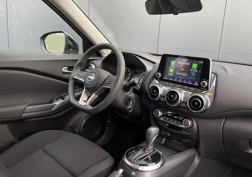 Intérieur du Nissan Juke 2024 côté conducteur, tableau de bord noir avec écran tactile et boîte automatique.