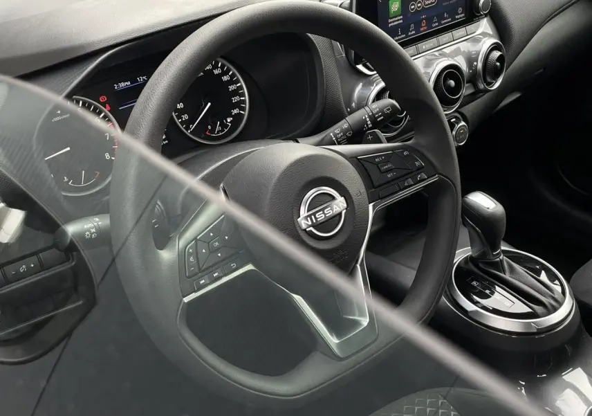 Vue intérieure rapprochée du volant et levier de vitesse d'une Nissan Juke 2024, avec tableau de bord et commandes visibles.