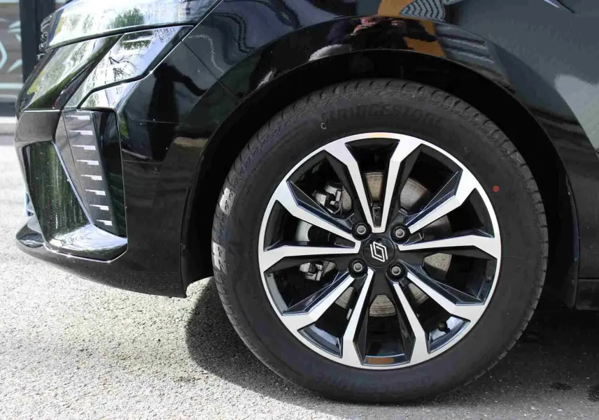 Gros plan sur la roue avant gauche noire étoile métal d’une Renault Clio 2025 avec jante alliage bicolore.