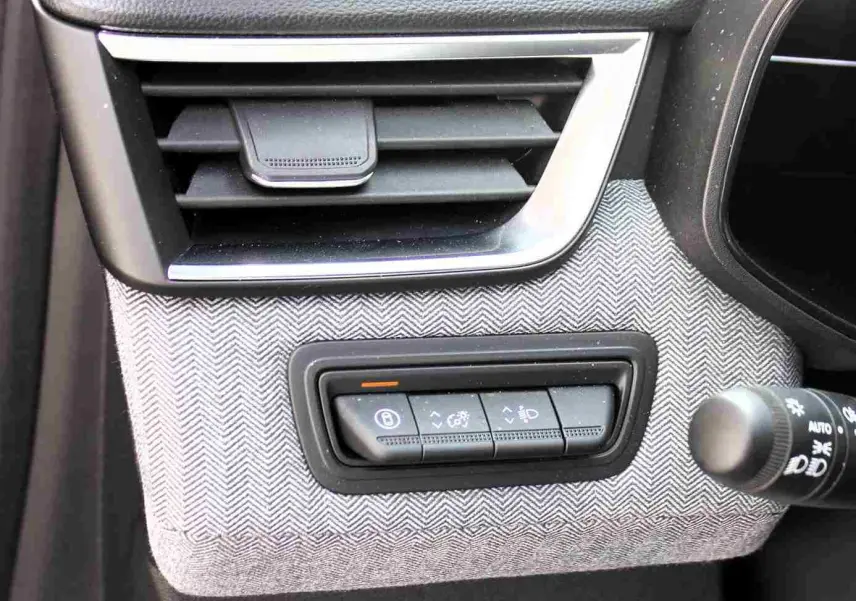 Détail intérieur de la Renault Clio 2025, panneau de commandes sous la sortie d'air avec finition tissu gris clair.