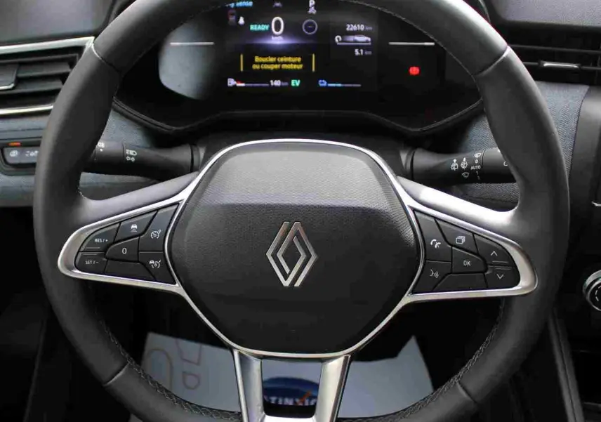 Vue rapprochée du volant noir de la Renault Clio 2025 avec commandes intégrées et tableau de bord numérique allumé.