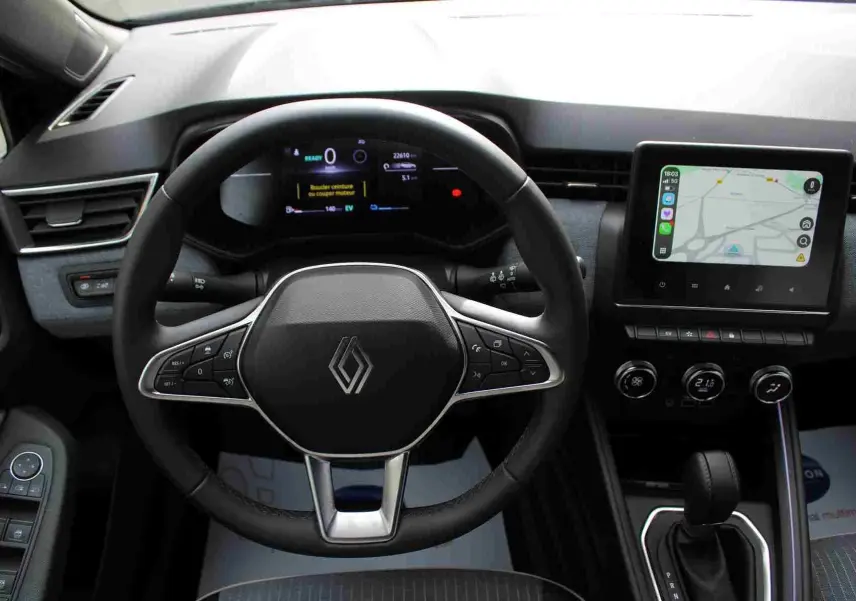 Vue intérieure centrée sur le volant et tableau de bord de la Renault Clio noire, avec écran tactile et commandes au volant.