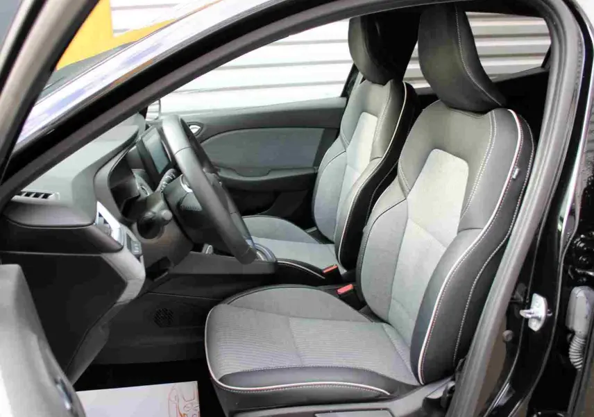 Vue intérieure côté conducteur de la Renault Clio 2025 noire étoile métal, sièges tissu gris clair avec surpiqûres blanches.