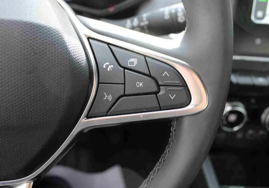 Gros plan sur les commandes au volant de la Renault Clio 2025, finition noire avec boutons de contrôle multifonctions.