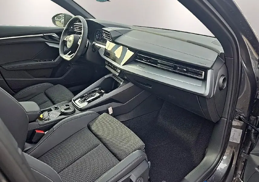Intérieur avant droit de l'Audi A3 Sportback 2026, sièges tissu gris et tableau de bord moderne noir et gris.