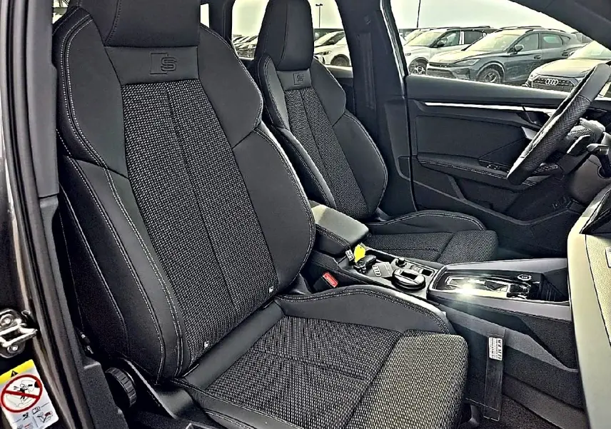 Vue intérieure côté gauche montrant les sièges sport noirs avec logo S et console centrale d'une Audi A3 Sportback 2026.