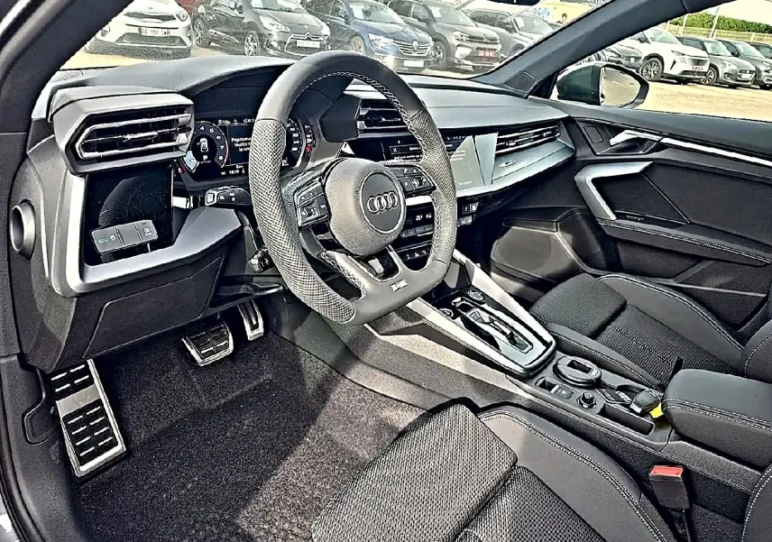 Intérieur Audi A3 Sportback 2026 vu côté conducteur, volant cuir sport et console centrale moderne noire.