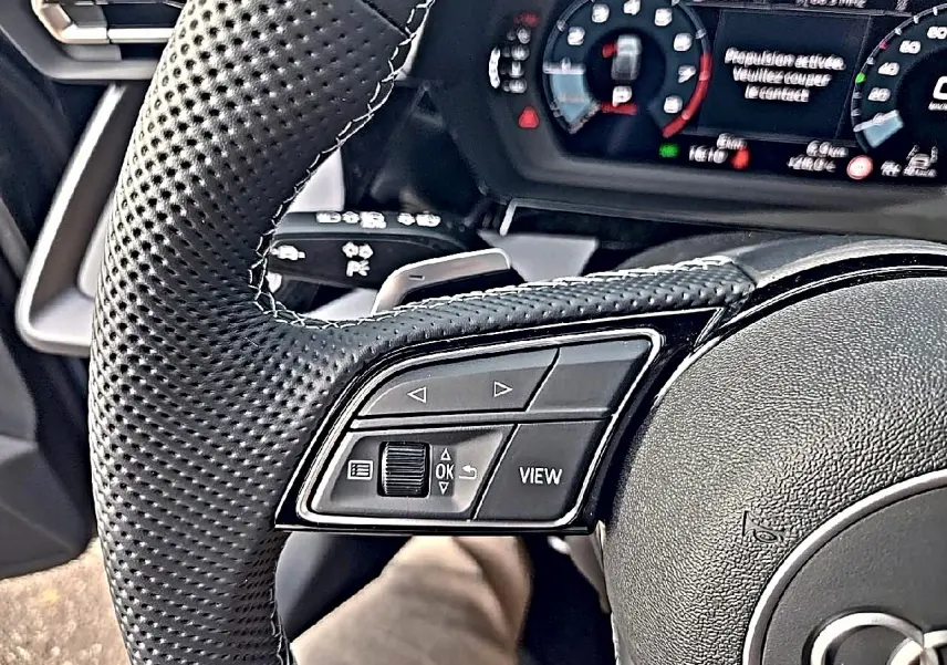 Gros plan sur le volant cuir perforé et les commandes multifonctions de l'Audi A3 Sportback 2026.