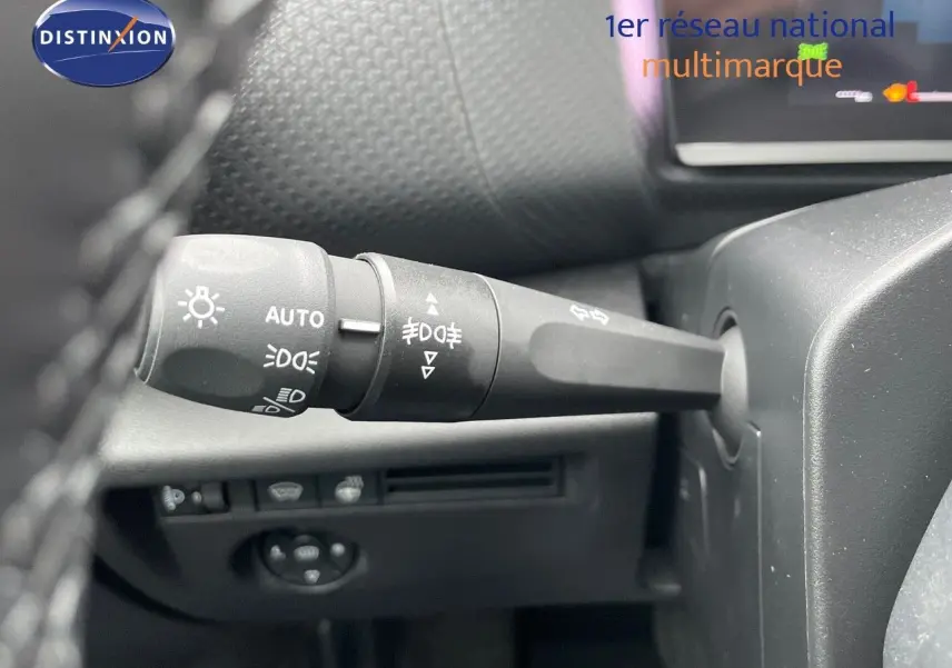 Gros plan sur la manette des feux et clignotants à gauche du volant dans l'habitacle d'une Citroën C4 blanche 2024.
