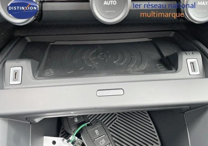 Gros plan sur la console centrale d'une Citroën C4 blanche métal 2024, avec recharge sans fil et ports USB visibles.
