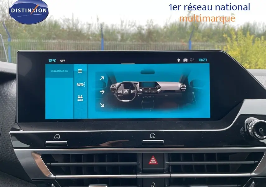 Écran tactile du tableau de bord de la Citroën C4 blanche, affichant les commandes de climatisation et la vue intérieure.