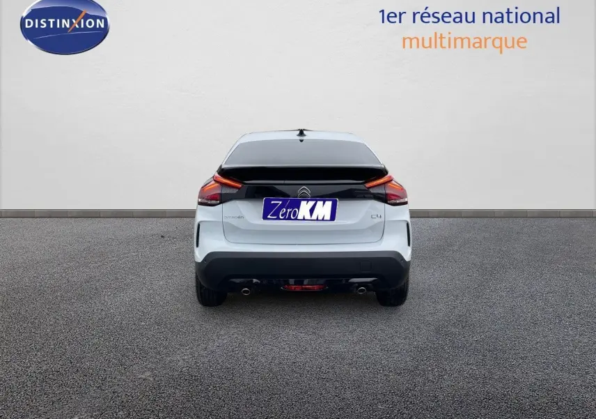 Vue arrière d'une Citroën C4 blanche métal 2024 avec feux LED et double sortie d'échappement visible sur sol gris.