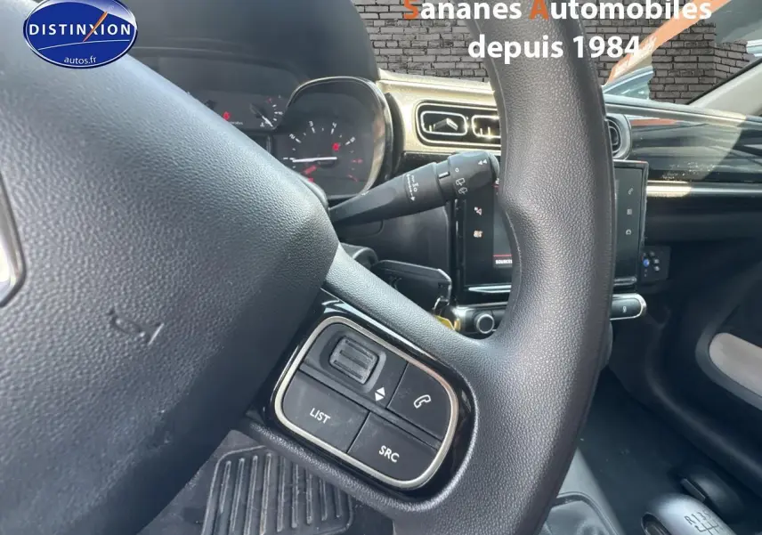 Gros plan sur les commandes audio au volant d'une Citroën C3 blanche de 2023, intérieur moderne avec tablette tactile.