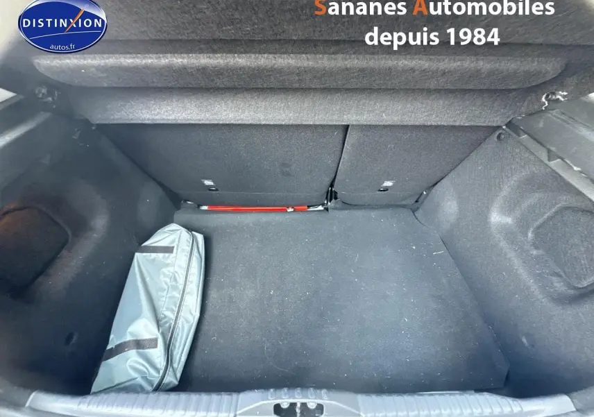 Coffre ouvert d'une Citroën C3 blanche 2023, vue de dessus montrant un sac gris à gauche et un intérieur noir.