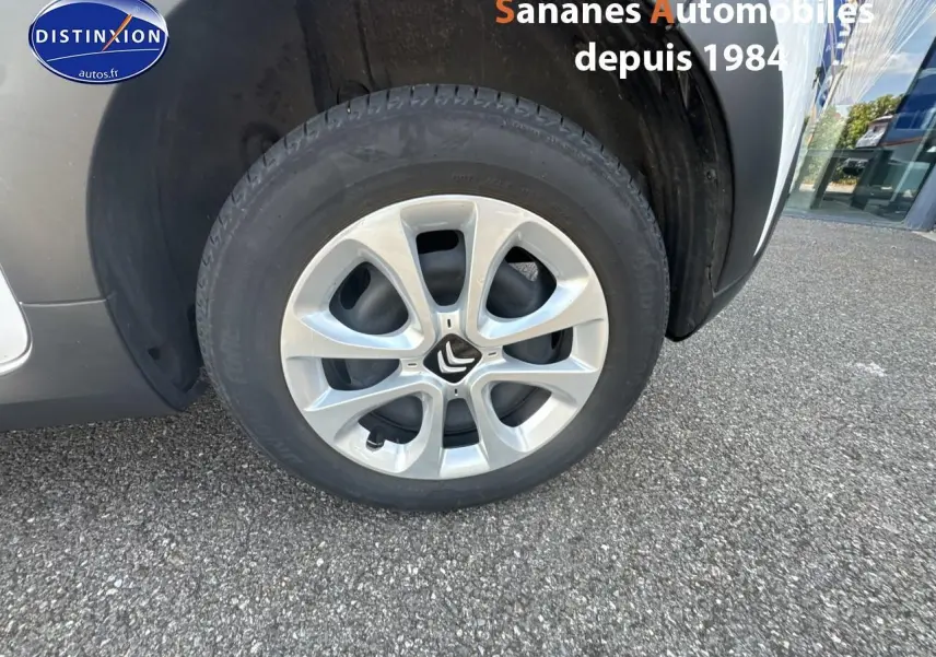 Gros plan sur la roue avant droite d'une Citroën C3 blanche avec jante argentée et élargisseur d'aile noir mat.