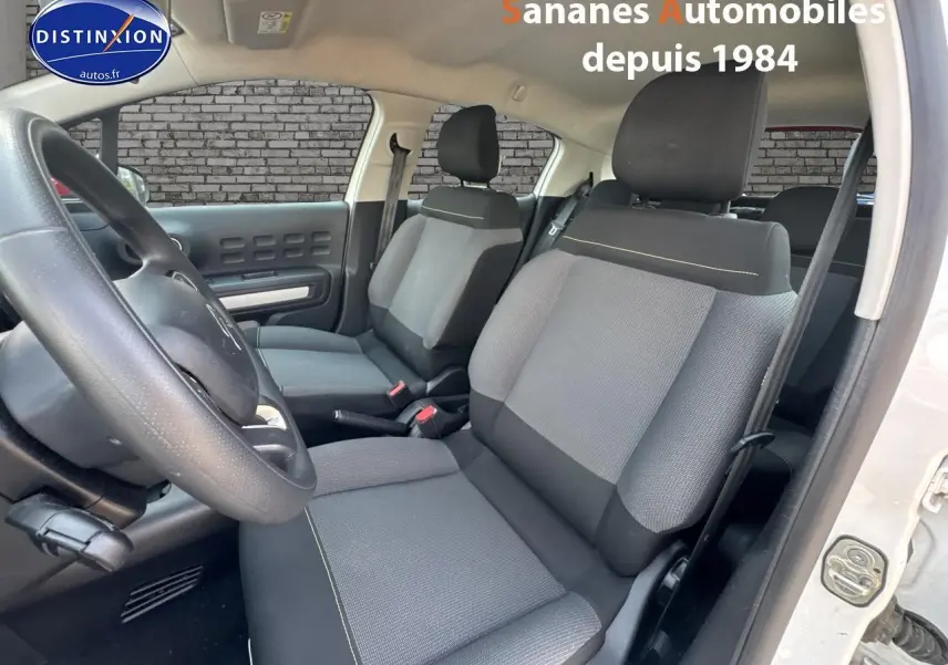 Intérieur de la Citroën C3 2023, vue côté conducteur, sièges tissu gris avec surpiqûres jaunes et volant noir.