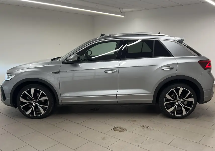 Profil côté gauche du Volkswagen T-Roc gris pyrite 2024 avec jantes 19 pouces et toit ouvrant panoramique.