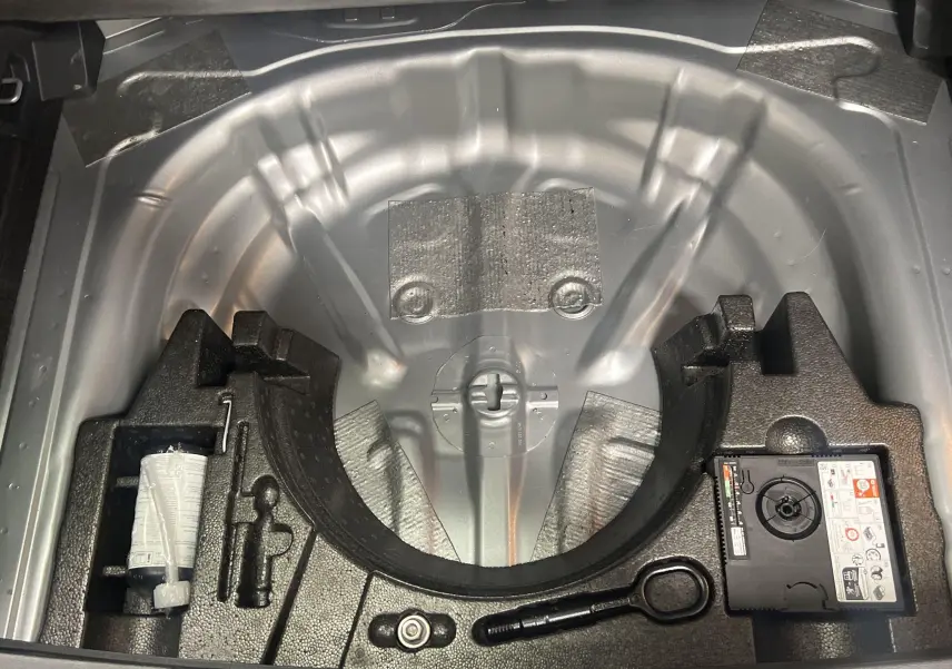 Coffre ouvert montrant le rangement sous plancher avec kit de réparation et espace pour roue de secours du Volkswagen T-Roc.