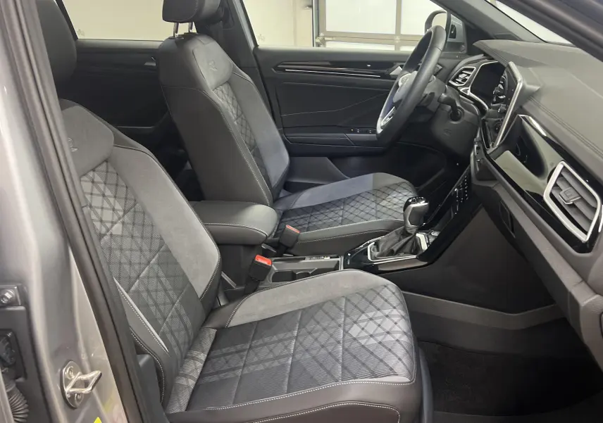 Vue intérieure côté conducteur du Volkswagen T-Roc 1.5 TSI R-Line 2024, sièges en tissu gris à motifs géométriques.
