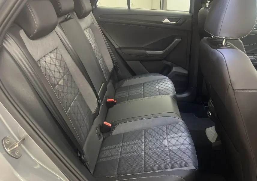 Vue intérieure arrière côté gauche du Volkswagen T-Roc 2024, sièges en cuir et tissu à motifs géométriques.