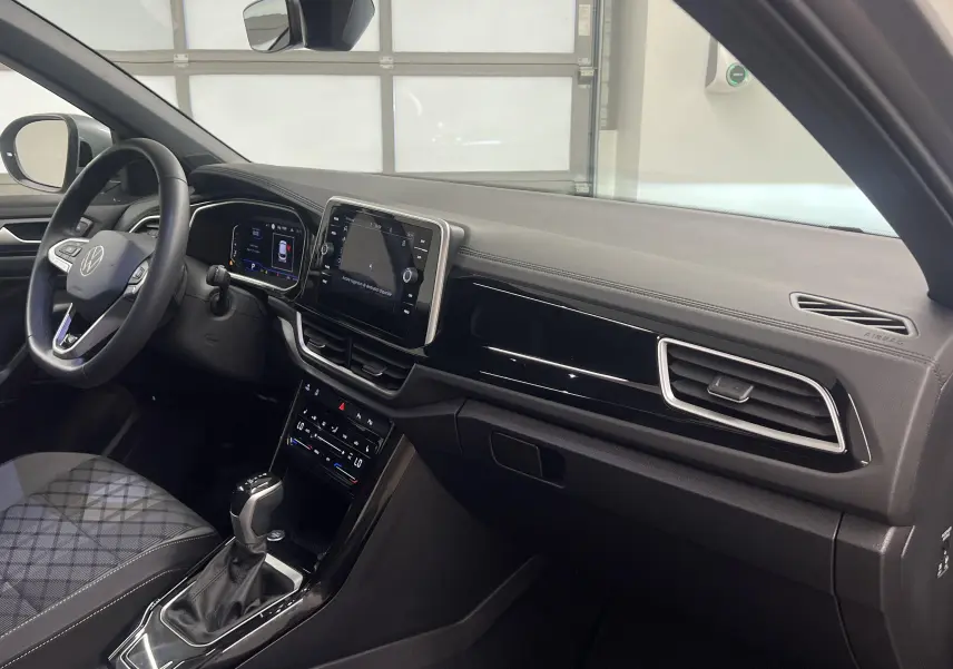 Intérieur avant droit du Volkswagen T-Roc 2024, tableau de bord moderne avec écran tactile et volant multifonction.