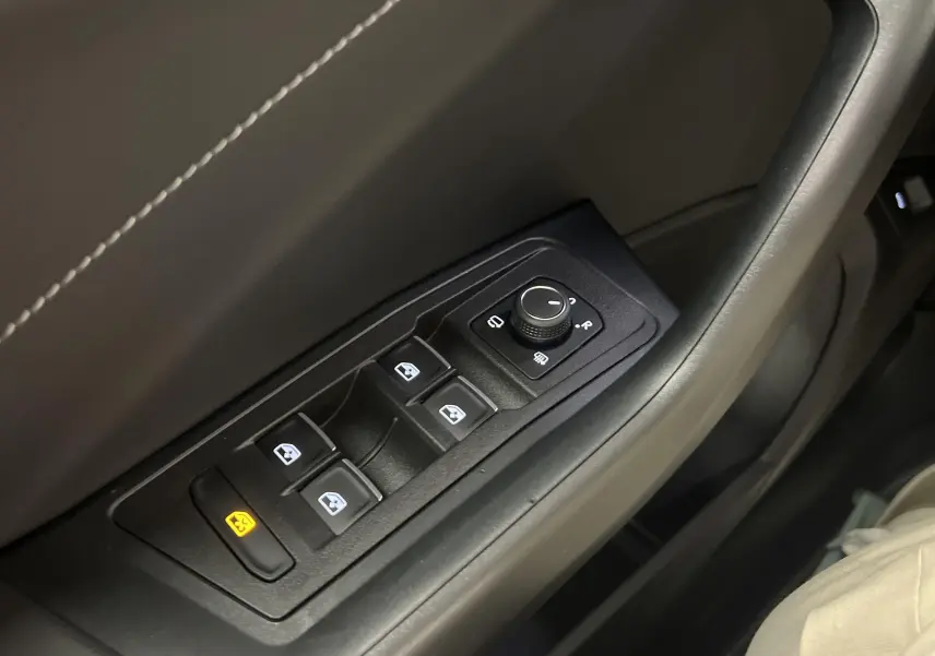 Gros plan sur les commandes de lève-vitres et rétroviseurs côté gauche du Volkswagen T-Roc 2024 finition R-Line.