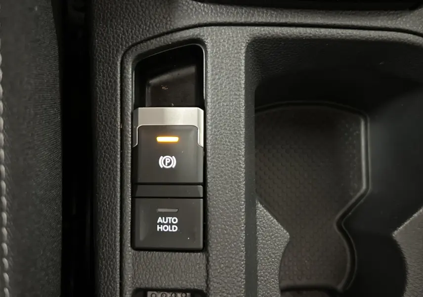 Gros plan sur la commande de frein de parking électronique et bouton Auto Hold dans le Volkswagen T-Roc 2024.