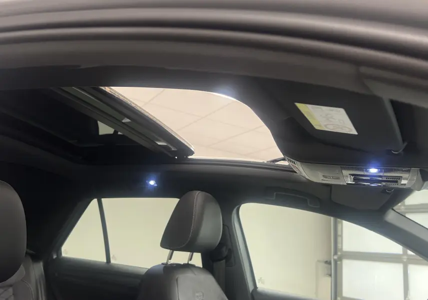 Intérieur du Volkswagen T-Roc 2024 avec toit ouvrant panoramique ouvert, sièges noirs et éclairage intérieur LED.