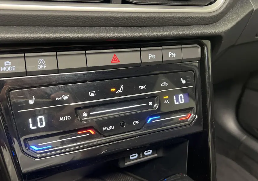 Gros plan sur la console centrale du Volkswagen T-Roc 2024, montrant la climatisation digitale et les commandes tactiles.
