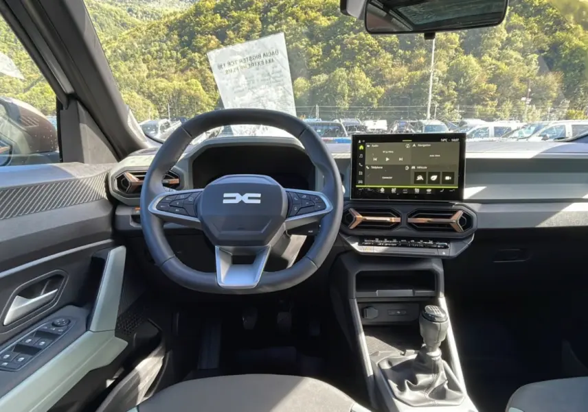 Vue intérieure avant du Dacia Bigster gris schiste 2025, volant multifonction, écran tactile 10 pouces et boîte manuelle.