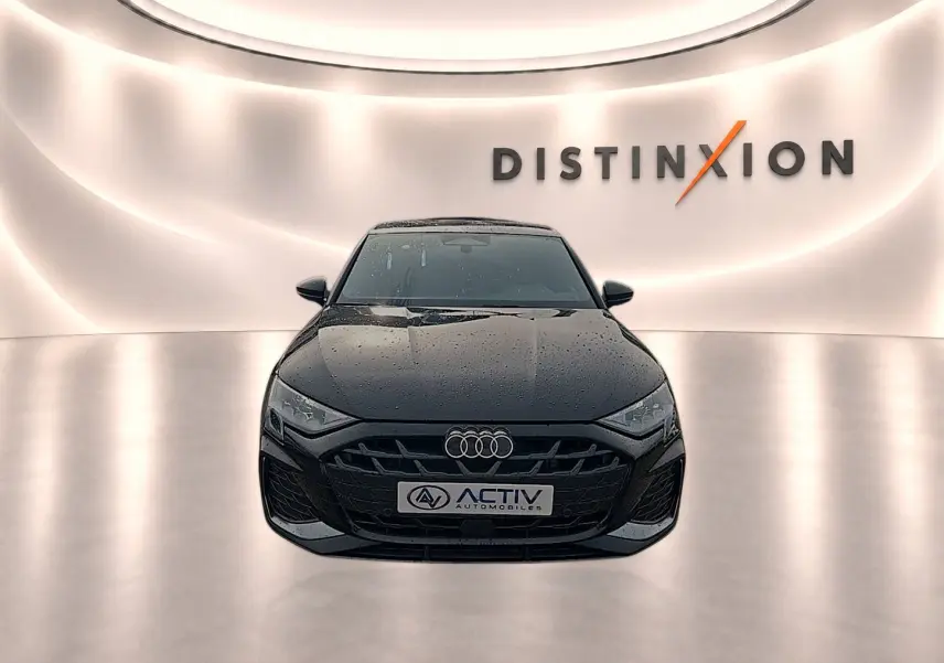 Vue avant d'une Audi A3 Sportback noire Mythos avec calandre S line et logo Audi visible sur fond lumineux Distinxion.