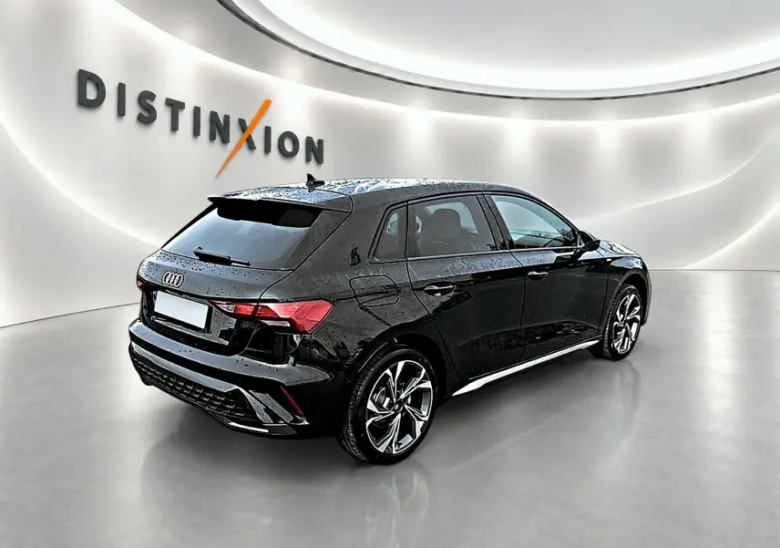 Audi A3 Sportback noir Mythos vue 3/4 arrière droit dans un showroom lumineux avec jantes alu graphiques.